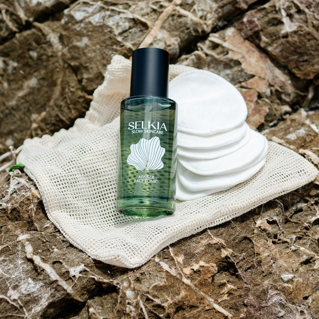 Australian made Selkia natural face tonic in sustainable glass jar with Selkia reuse-able facial pads and Selkia mesh carrier bag on rock background
