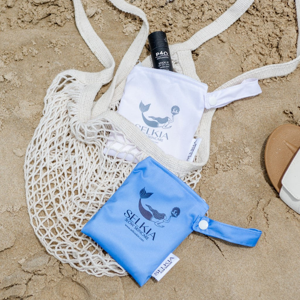 Australian made Selkia blue and white colour washable carrier bag with P40 SPF 50 sunscreen stick and mesh carrier bag with sandy beach background